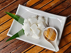 Tasty coconut milk serve with caramel sauce decorated with flower is on wooden table