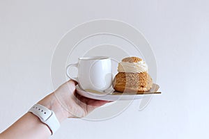 Tasty coffee and craquelin choux pastry cream-puff dessert filled with cream on a plate.