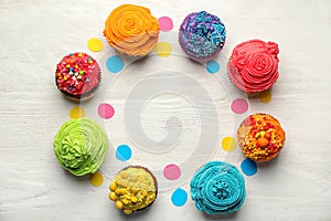 Tasty colorful cupcakes on white wooden table