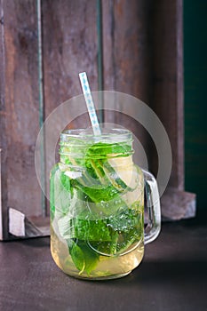 Tasty colorful drink with cold green tea, mint and cucumber in a glass jar on a vintage background