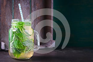 Tasty colorful drink with cold green tea, mint and cucumber in a glass jar on a vintage background