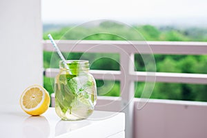 Tasty colorful drink with cold green tea, mint and lemon in a glass jar on a white kitchen background