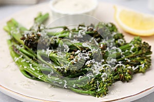 Tasty cooked broccolini with cheese on plate, closeup
