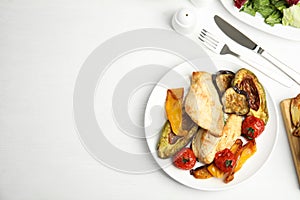 Tasty cooked chicken fillet and vegetables served on white wooden table, flat lay with space for text. Healthy meals from air