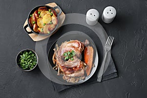 Tasty cooked rabbit meat with vegetables and potato served on black table, flat lay