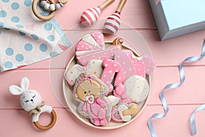 Tasty cookies of different shapes and toys on pink wooden table, flat lay. Baby shower party