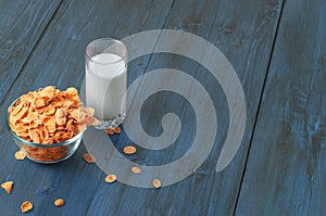 Tasty corn flakes in bowl with glass of milk