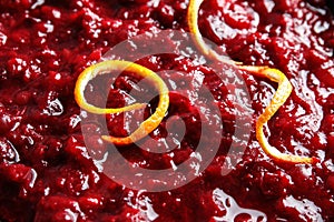 Tasty cranberry sauce with citrus zest as background