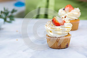 Tasty cream cheese cupcakes. Woman cooking cakes. Confectioner decorating cupcakes with strawberry. Cooking class, culinary and