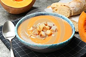 Tasty creamy pumpkin soup with croutons and seeds in bowl on table