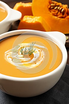 Tasty creamy pumpkin soup with dill and seeds in bowl on table