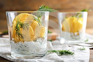 Tasty crispy potato chips with sour cream and dill in glass