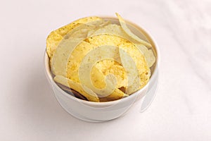 Tasty crispy potato chips in white bowl