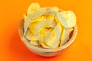 Tasty crispy potato chips in wooden bowl