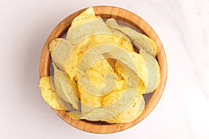 Tasty crispy potato chips in wooden bowl