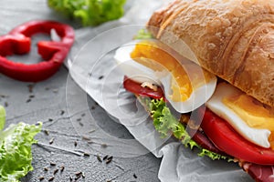 Tasty croissant sandwich with boiled egg on grey table