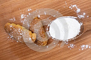 Tasty croissants on brown wooden background. Flour in wooden spoon. Top view