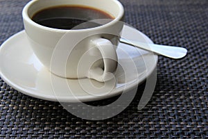 Tasty cup of steaming coffee on patterned placemat