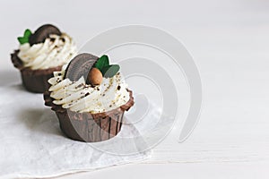 Tasty cupcake, decorated with chocolate cookies on a white wooden background