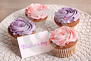 Tasty cupcakes with card for Mother's day on plate