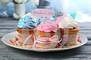 Tasty cupcakes and topper pick with words MOTHER'S DAY on table