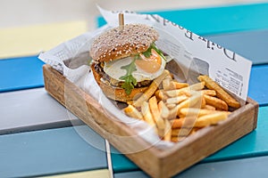 Tasty delicious home made burgers with French fries in wooden plate