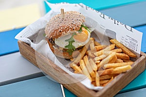 Tasty delicious home made burgers with French fries in wooden plate