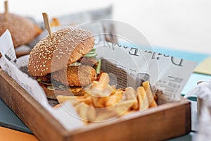 Tasty delicious home made burgers with French fries in wooden plate