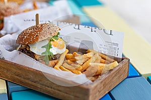 Tasty delicious home made burgers with French fries in wooden plate