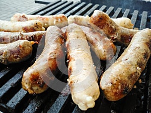 Tasty delicious sausages are cooked on coals. Summer picnic concept. Grilled sausages roasting on BBQ grill outdoor. Grilled food