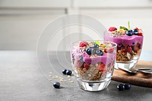 Tasty dessert with acai smoothie, granola and berries on grey table. Space for text