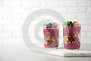 Tasty dessert with acai smoothie, granola and berries on marble table. Space for text