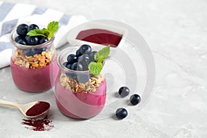 Tasty dessert with acai smoothie, granola and berries on marble table. Space for text