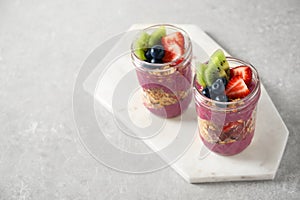 Tasty dessert with acai smoothie, granola and berries on marble table. Space for text