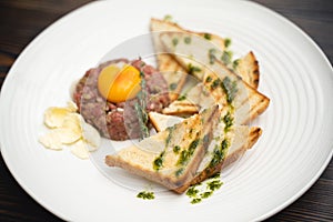 A tasty dish of meat and egg yolk with croutons on a plate