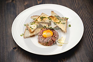 A tasty dish of meat and egg yolk with croutons on a plate