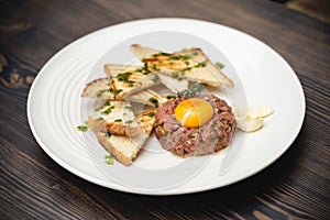 A tasty dish of meat and egg yolk with croutons on a plate