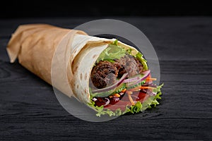 Tasty doner kebabs with fresh salad trimmings and shaved roasted meat served in tortilla wraps on brown paper as a