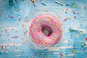 Tasty donut with pink icing and colorful sprinkles