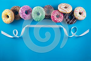 Tasty donuts with white ribbon on blue background with a space for text.