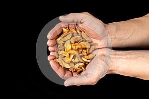 Tasty dried apple slices in male hands on black background