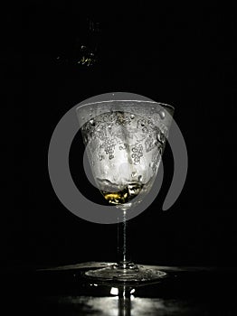 Tasty drink pouring in beautiful misted vintage glass, black background