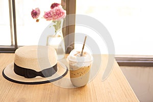 Tasty drinking, cup of ice cappuccino coffee decorated with white milk froth in a tall plastic glass on brown wooden table