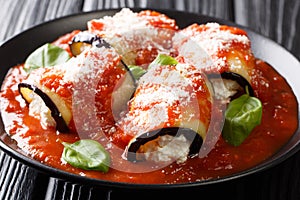 Tasty eggplant rolls stuffed with cheese and baked in tomato sauce close-up in a plate. horizontal