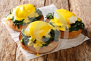 Tasty Eggs Benedict with spinach and hollandaise sauce on a toasted bun close-up. Florentine eggs. horizontal
