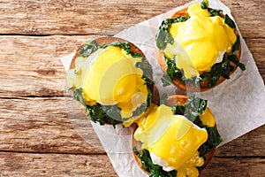 Tasty Eggs Benedict with spinach and hollandaise sauce on a toasted bun close-up. Florentine eggs. Horizontal top view