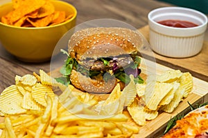 Tasty fast food on table. Pepperoni pizza and pizza Capricciosa , hamburger and potato chips