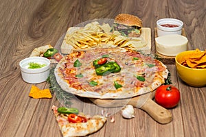 Tasty fast food on table. Pepperoni pizza and pizza Capricciosa , hamburger and potato chips