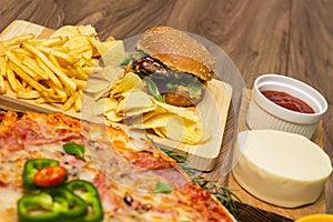 Tasty fast food on table. Pepperoni pizza and pizza Capricciosa , hamburger and potato chips