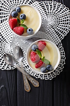 Tasty food: vanilla pudding with raspberries and blueberries close-up. Vertical top view